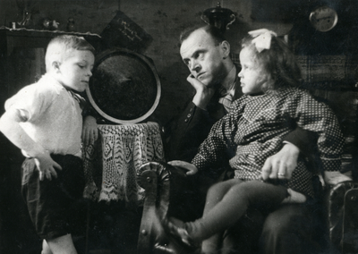 845940 Portret van Marinus Luiten met zijn kinderen Cor (links) en Riek luisterend via de radiodistributie naar de ...